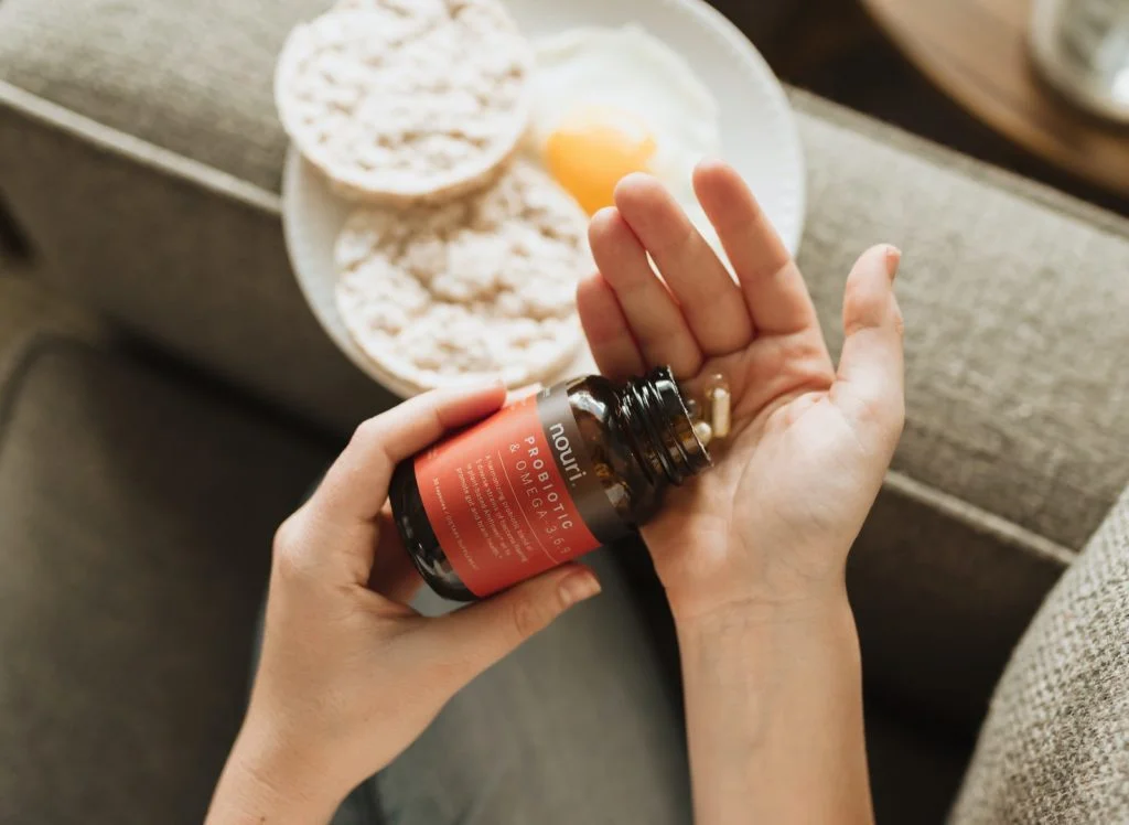 person holding red bottle as an example of vitamin B12 supplement