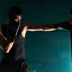 man in black tank top and black shorts wearing black boxing gloves